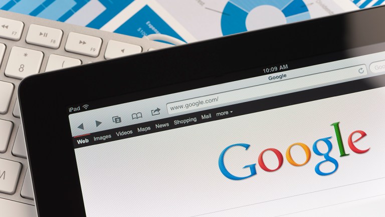 Close up of an Apple Ipad and on a desk showing the Google search engine.