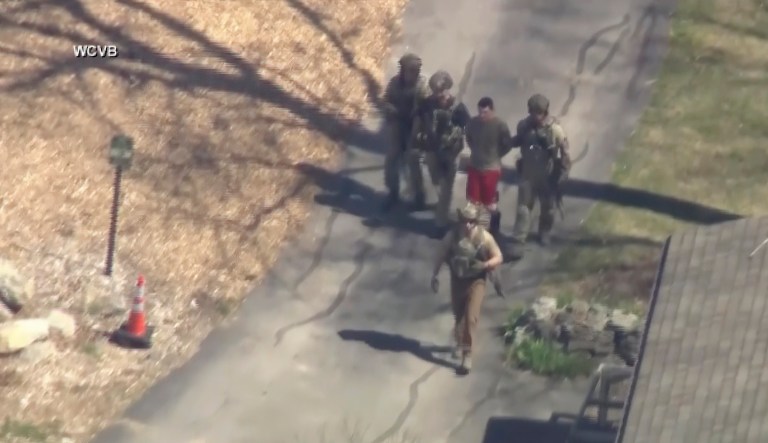 This image made from video provided by WCVB-TV, shows Jack Teixeira, in T-shirt and shorts, being taken into custody by armed tactical agents on Thursday, April 13, 2023, in Dighton, Mass.