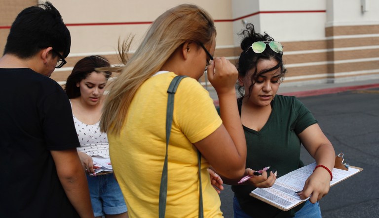 In this Aug. 15, 2018, photo, Maria Nieto, right, and Alma Romo, second from left, register people to vote in Las Vegas. Democrats in Nevada are working to register and engage Latino voters ahead of this year's midterms, hoping to recreate the big wins that the state's Hispanic and immigrant community are credited with delivering two years ago.