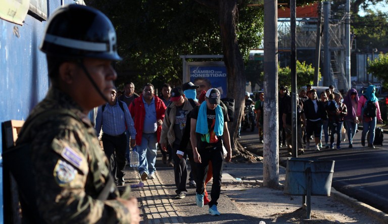 Police stand by as locals begin their journey north toward the U.S. border, during a migrant caravan passing through the capital of San Salvador, El Salvador, early Wednesday, Jan. 16, 2019.