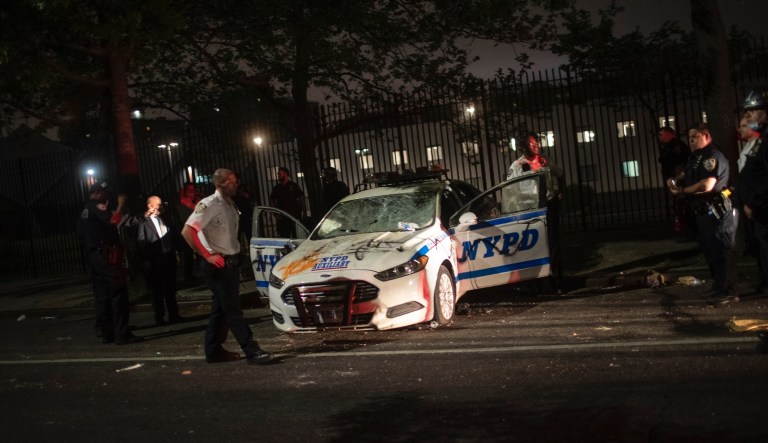 A police officer talks to people who have arrived to line up outside Elmhurst Hospital Center to be tested for the coronavirus, Tuesday, March 24, 2020, in the Queens borough of New York.