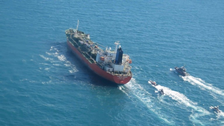 FILE - In this July 21, 2019, file photo, a speedboat of the Iran's Revolutionary Guard moves around a British-flagged oil tanker Stena Impero, which was seized on Friday by the Guard, in the Iranian port of Bandar Abbas.