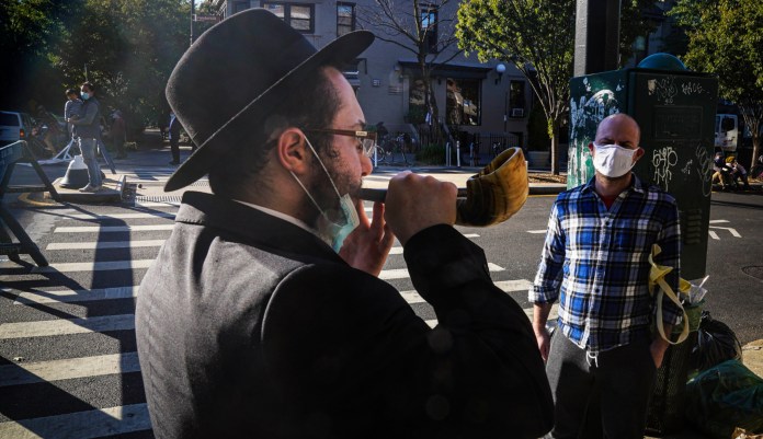 In this Sept. 20, 2020, file photo, an Orthodox Jewish man blows the Shofar after a brief prayer with a passerby in New York. Amid a new surge of COVID-19 in New Yorkâs Orthodox Jewish communities, many residents are reviving health measures that some had abandoned over the summer â social distancing, wearing masks. For many, thereâs also a return of anger: They feel the city is singling them out for criticism that other groups avoid. (AP Photo/Bebeto Matthews, File)