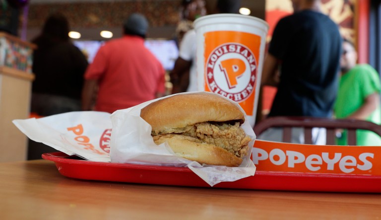 A chicken sandwich sits on a table at a Popeyes as guests wait in line, Thursday, Aug. 22, 2019, in Kyle, Texas.