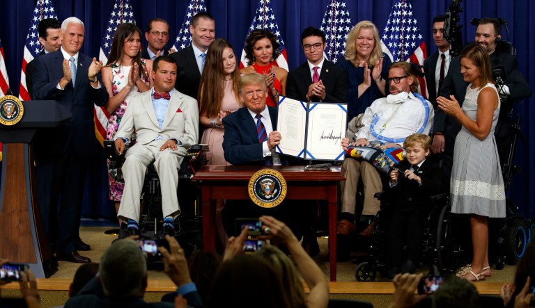 President Donald Trump holds up the "Right to Try" act after signing it in the South Court Auditorium on the White House campus, Wednesday, May 30, 2018, in Washington.