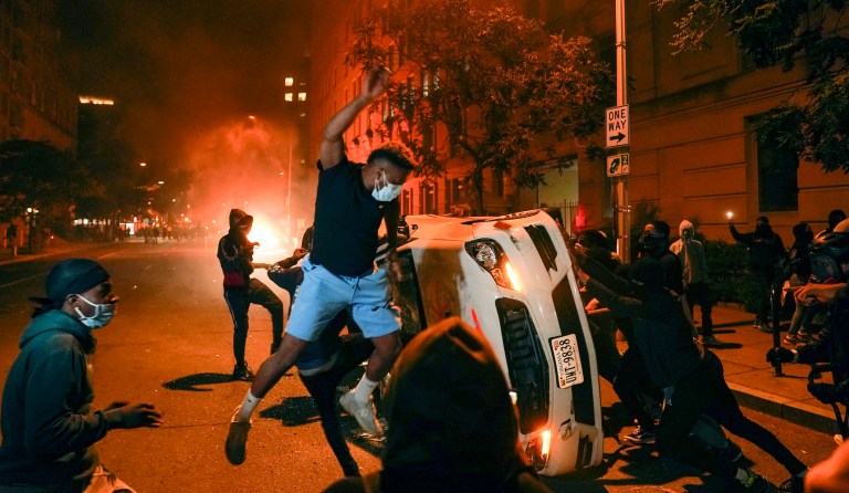 Demonstrators vandalize a car as they protest the death of George Floyd, Sunday, May 31, 2020, near the White House in Washington. 