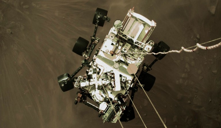 This Thursday, Feb. 18, 2021 photo provided by NASA shows the Perseverance rover lowered towards the surface of Mars during its powered descent.