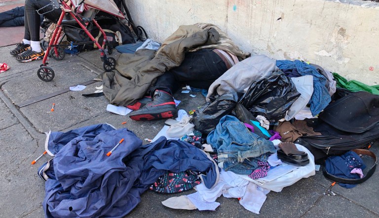 FILE - In this July 25, 2019, file photo, sleeping people, discarded clothes and used needles are seen on a street in the Tenderloin neighborhood in San Francisco.