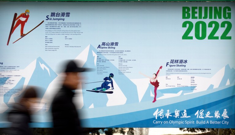 People walk past a display introducing winter sporting events for the upcoming Beijing 2022 Winter Olympics at a temple fair at Longtan Park in Beijing, Wednesday, Feb. 6, 2019. 