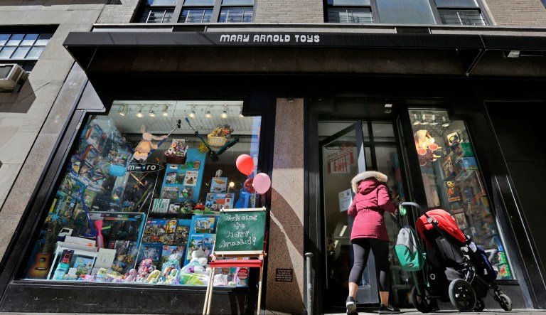 In this Monday, March 19, 2018, photo, a woman pushes a stroller as she enters Mary Arnold Toys in Manhattan's Upper East Side. Mary Arnold, a nearly 90-year-old store in Manhattan, is thriving along with many other small and independent toy stores, even as Toys R Us is going out of business and more consumers shop online.