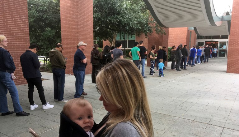 Megan Heckel of Plano holds her daughter Lily as they wait in line for early voting outside Maribelle M. Davis Library in Plano, Texas, Monday, Oct. 22, 2018. 