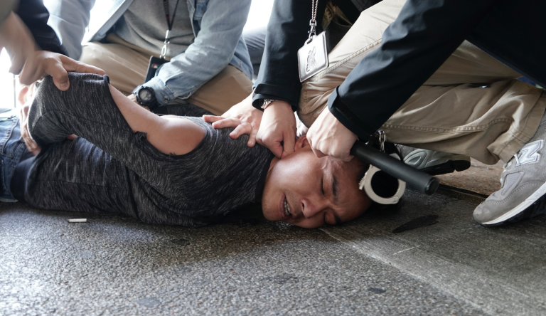 In this Wednesday, Dec. 18, 2019, file photo, a man is detained by police officers after being snatched a placard of Chinese President Xi Jinping and Hong Kong Chief Executive Carrie Lam from pro-democracy activists at a ferry terminal in Hong Kong. A ferry company barred a Hong Kong activist "Long Hair", whose real name is Leung Kwok-hung, from boarding a boat Wednesday to Macao, where Chinese President Xi Jinping is slated to arrive for the 20th anniversary of Macau's return to China, (AP Photo/Kin Cheung, File)