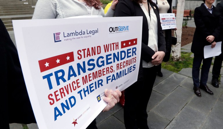 FILE - In this March 27, 2018 file photo, plaintiffs Cathrine Schmid, second left, and Conner Callahan, second right, listen with supporters during a news conference in front of a federal courthouse following a hearing in Seattle. Transgender-rights activists are angered at moves by President Donald Trump and his administration to undermine gains achieved before his election. Trump is seeking to ban transgender people from military service, although that effort has stalled in court.