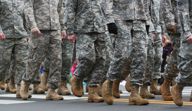 Soldiers dressed in Army camouflage march an a parade.