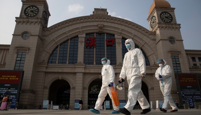Workers in protective overalls walk past the Hankou railway station on the eve of its resuming outbound traffic in Wuhan in central China's Hubei province on Tuesday, April 7, 2020. Just after midnight Wednesday, the city's 11 million residents will be permitted to leave without special authorization as long as a mandatory smartphone application shows they are healthy and have not been in recent contact with anyone confirmed to have the virus. 
