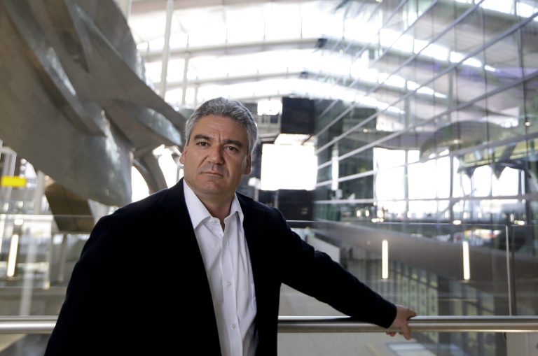 Luis Vidal, Concept and Lead Architect poses for a photograph at the new Heathrow Terminal 2 in London, Wednesday, April 23, 2014, next to the sculpture 'Slipstream', left, by artist Richard Wilson which will be the longest permanent sculpture in Britain, measuring 78 metres and weighing 77 tonnes.  The 2.5 billion pound ($4.2 billion) new Terminal 2 is due to open to the public in June after 5-years in development, to handle the anticipated 20 million passengers per year. (AP Photo/Kirsty Wigglesworth)