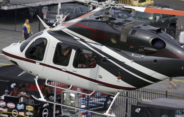Driver Kurt Busch waves as he arrives in a helicopter for the NASCAR Sprint Cup series Coca-Cola 600 auto race at the Charlotte Motor Speedway in Concord, N.C., Sunday, May 25, 2014. Busch raced in the Indianapolis 500 earlier Sunday. (AP Photo/Gerry Broome)