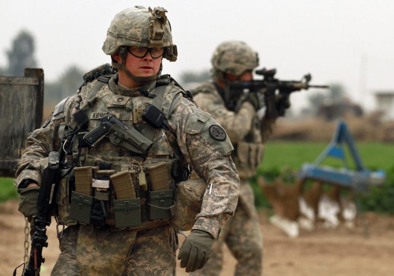 In this Tuesday, Jan. 25, 2011 photo, U.S. Army Staff Sgt. Marc Krugh, left, from the 3rd Armored Cavalry Regiment, looks on as a comrade peers through the scope on his weapon during a patrol near Iskandariyah, 30 miles (50 kilometers) south of Baghdad. (AP Photo/Maya Alleruzzo)