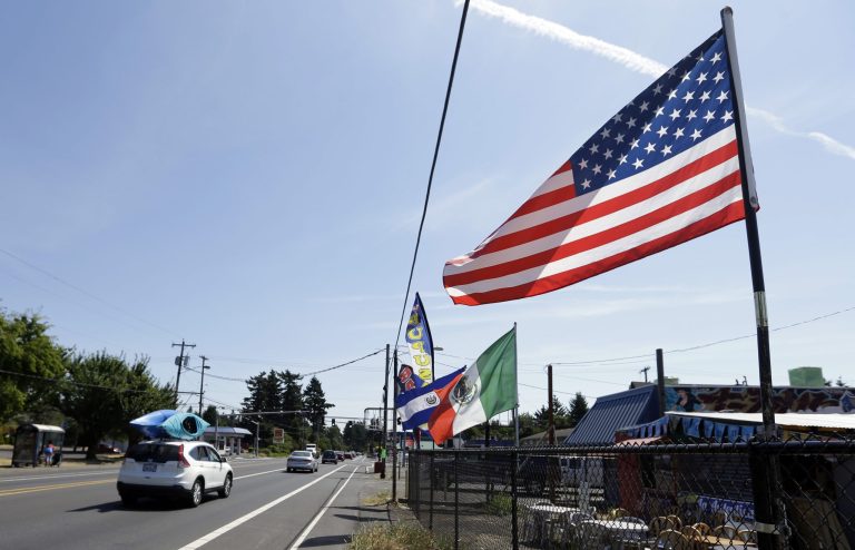 In this Monday, July 6, 2015 photo, an American flag is joined by flags from Mexico and El Salvador adorning a fence along Powell Boulevard in East Portland, Ore.(AP Photo/Don Ryan)