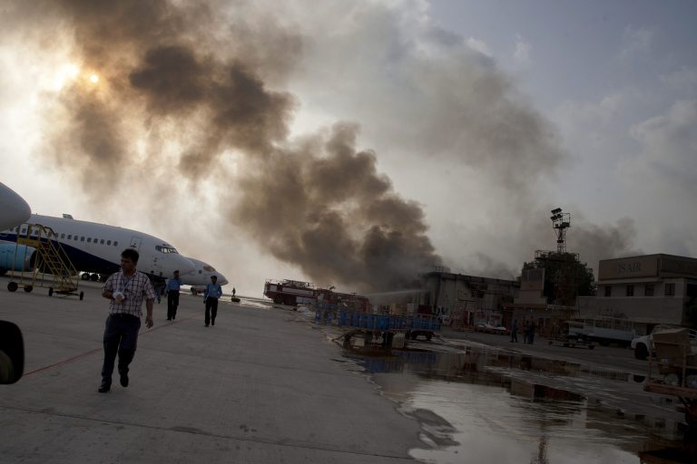 Smoke rises above Karachi airport terminal Monday, June 9, 2014 in Pakistan. Gunmen disguised as police guards attacked the terminal with machine guns and a rocket launcher during a five-hour siege that killed 13 people as explosions echoed into the night, while security forces retaliated and killed all the attackers, officials said Monday. (AP Photo/Shakil Adil)