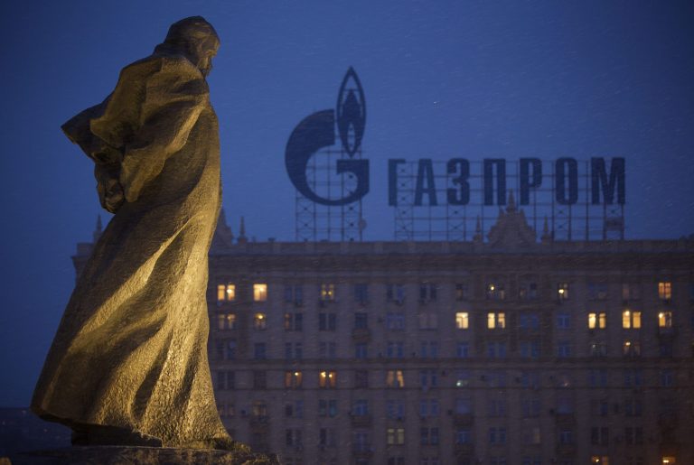 A monument to Ukrainian poet and writer Taras Shevchenko is silhouetted against an apartment building with a sign advertising Russia's natural gas giant Gazprom, in Moscow, Russia, Tuesday, March 4, 2014. (AP Photo/Alexander Zemlianichenko)