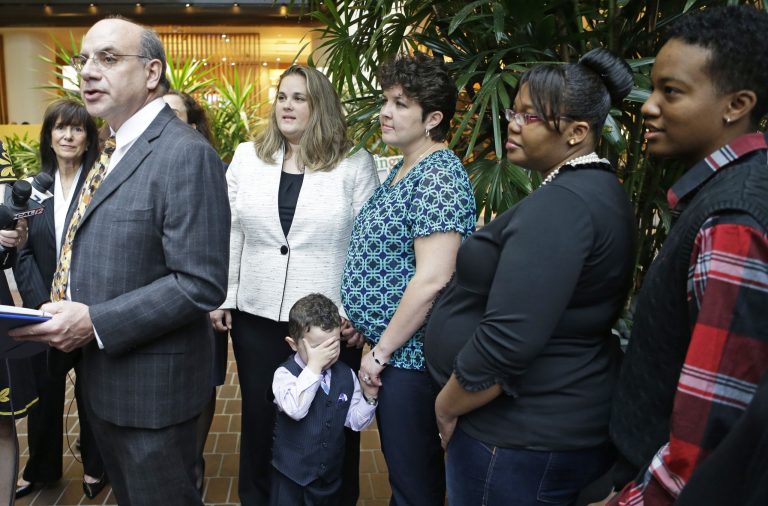 Attorney Al Gerhardstein, left, stands with several same-sex couples at a news conference, Friday, April 4, 2014, in Cincinnati. Civil rights attorneys are arguing in Federal Court on Friday that a federal judge should prohibit Ohio officials from enforcing the state's ban on gay marriage. (AP Photo/Al Behrman)