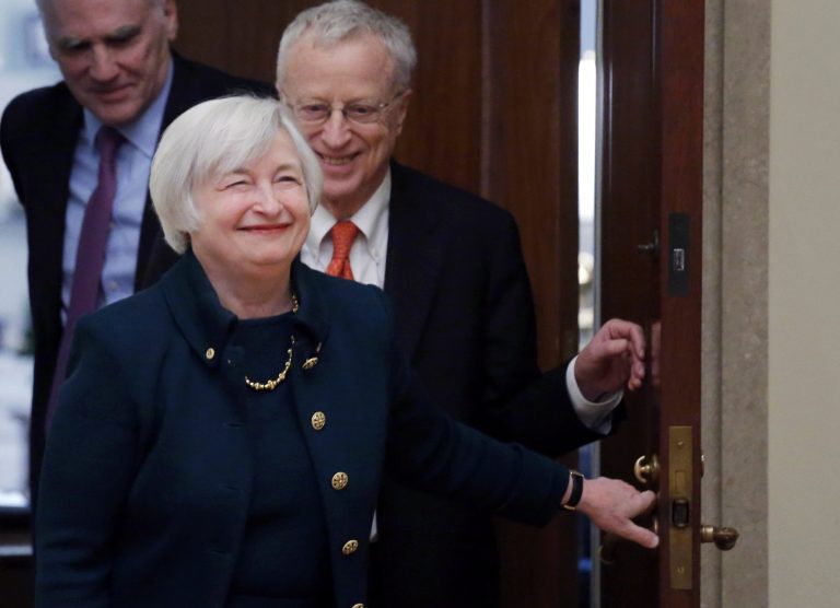 FILE - In this Monday, Feb. 3, 2014, file photo, Janet Yellen, followed by her husband, Nobel Prize winning economist George Akerlof, smiles as she walks into a room of applause by staff members before she is administered the oath of office as Federal Reserve Board chair, at the Federal Reserve in Washington. Yellen is the first woman to lead the Federal Reserve. (AP Photo/Charles Dharapak, File)