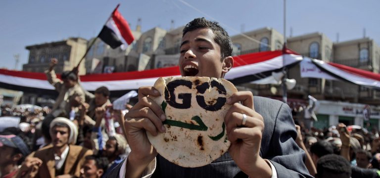 FILE - In this Saturday, Feb. 26, 2011 file photo, an anti-government protestor chants slogans and holds a piece of bread that reads in Arabic, 