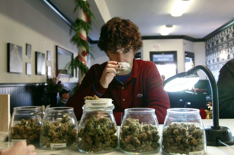 File - In this Dec. 15, 2011 file photo, medical marijuana patient Kevin Brown smells marijuana available at The Apothecarium Medical Cannabis Dispensary in San Francisco. California cities and counties can ban medical marijuana dispensaries, the state's highest court ruled Monday in a unanimous opinion likely to further diminish California's once-robust medical marijuana industry. The California Supreme Court said neither the state's voter-approved law legalizing medical marijuana nor a companion measure adopted by the Legislature prevent local governments from using their land use and zoning powers to prohibit storefront dispensaries. (AP Photo/Jeff Chiu, file)
