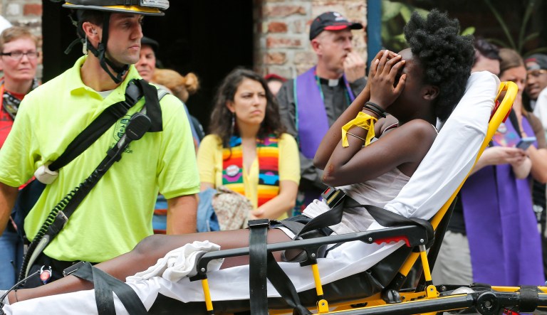 Rescue personnel help an injured woman after a car ran into a large group of protesters after an white nationalist rally in Charlottesville, Va., Saturday, Aug. 12, 2017. (AP Photo/Steve Helber)