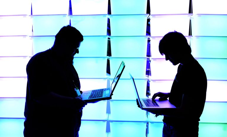 Participant hold their laptops in front of an illuminated wall at the annual Chaos Computer Club (CCC) computer hackers' congress, called 29C3, on December 28, 2012 in Hamburg, Germany. (Photo by Patrick Lux/Getty Images)