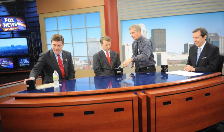 FOX News Sunday moderator Chris Wallace, far right, talks with Kentucky U.S. Senate candidates Democrat Jack Conway, left, and Republican Rand Paul as stage manager Rick Markley, standing, pours water in Louisville, Ky., Sunday, Oct. 3, 2010. (AP Photo/Patti Longmire)