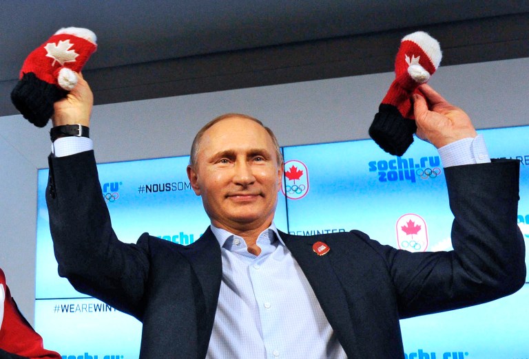 Russian President Vladimir Putin shows handmade mittens presented to him at Canada House during the 2014 Winter Olympics, Friday, Feb. 14, 2014 in Sochi, Russia. At left is Chairman of the Canadian National Olympic Committee Marcel Aubut.  (AP Photo / RIA-Novosti, Mikhail Klimentyev, Presidential Press Service)