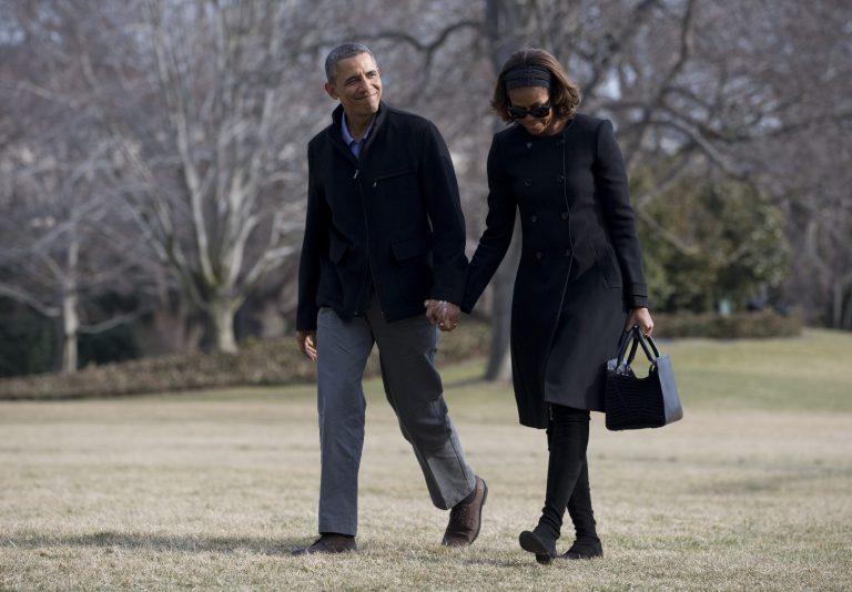 President Barack Obama and first lady Michelle Obama walk hand in hand across the South Lawn to the White House, Sunday, March 9, 2014, in Washington, as they arrive from Florida. (AP Photo/Carolyn Kaster)