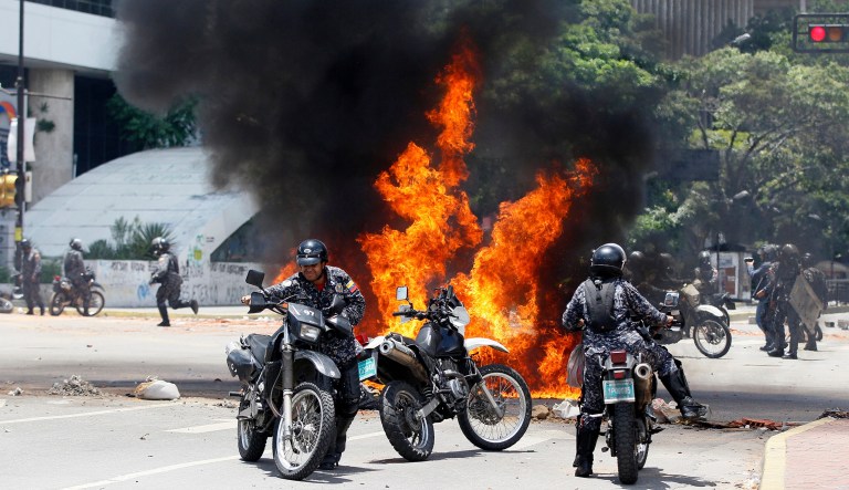 Venezuelan Bolivarian National police move away from the flames after an explosion during clashes against anti-government demonstrators in Venezuela. (AP Photo/Ariana Cubillos)