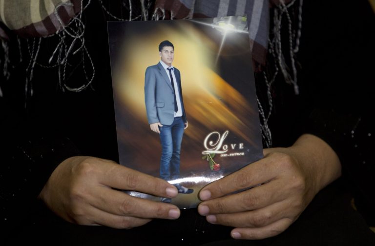 In this Tuesday, Sept. 16, 2014 photo, Palestinian Ahlam Abu Toaimeh, 47, holds a picture of her son Mohammed Abu Toaimeh, 22, as she speaks to an Associated Press reporter at her house in the town of Abasan, in the southern Gaza Strip. Desperate to flee Gaza after suffering through years of border closures and three wars, Mohammed paid traffickers to smuggle him to Europe. But he and dozens of other Gazans are missing amid reports that smugglers sunk their vessel on purpose. (AP Photo/Khalil Hamra)