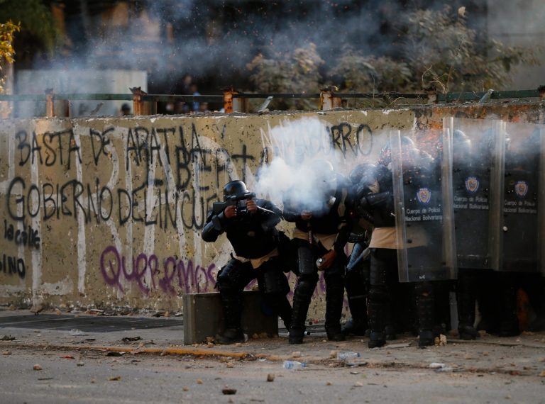 Bolivarian national police officers fire teargas at demonstrators  during clashes in Caracas, Venezuela, Wednesday, March 5, 2014. The one year anniversary of the death of Venezuela's former President Hugo Chavez was marked with a mix of street protests and solemn commemorations that reflected deep divisions over the Venezuela he left behind.