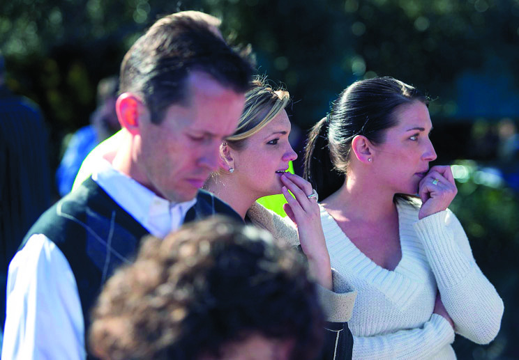 People watch a women being taken to a paramedic truck from an office building where a shooter opened fire in north central Phoenix on Wednesday, Jan. 30, 2013. (AP Photo/The Arizona Republic, Michael Schennum)