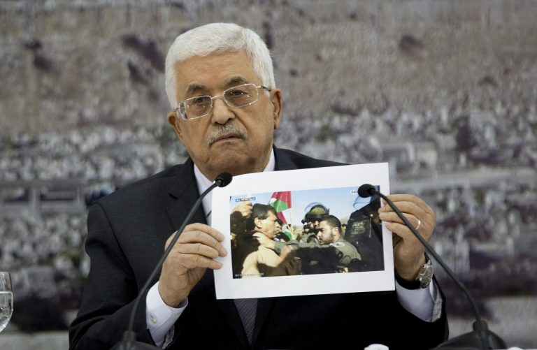 Palestinian President Mahmoud Abbas holds a picture of an Israeli soldier pushing Palestinian Cabinet minister Ziad Abu Ain during the meeting of the Palestinian leadership at his compound in the West Bank city of Ramallah, Dec. 10, 2014. Abu Ain died shortly after a protest in the village of Turmus Aya, near Ramallah, during which witnesses said Israeli troops fired tear gas at him and dozens of Palestinians marchers. Witnesses also said Abu Ain, was beaten by an Israeli soldier. (AP Photo/Majdi Mohammed)