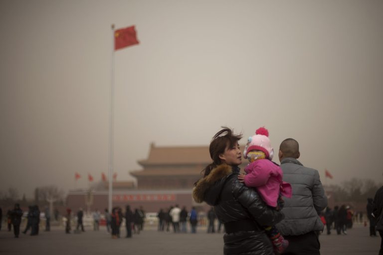 A woman holds her daughter, wearing a mask, while the family visit Tiananmen Square on a hazy day in Beijing, China, Thursday, Feb. 28, 2013. Pollution worsened in China's capital and surrounding regions on Thursday, as the country's new leaders geared up for a major congress where experts expect pollution to be on the agenda. (AP Photo/Alexander F. Yuan)