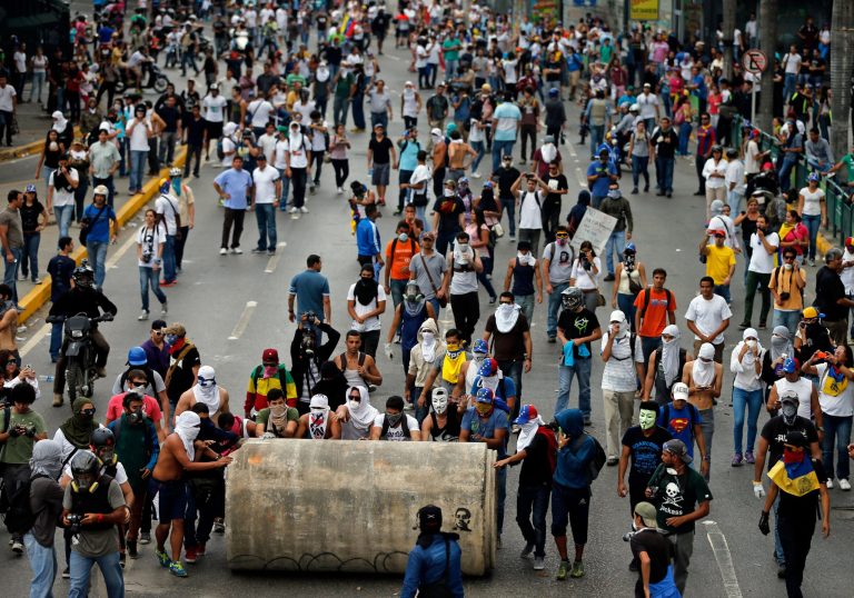 Demonstrators roll a water pipe in an attempt to block a major highway during clashes with the Bolivarian National Guard in Caracas, Venezuela, Thursday, Feb. 27, 2014. Anti-government protesters rallied to demand an end to the government crackdown on protests and the release of those jailed in recent weeks.  (AP Photo/Fernando Llano)