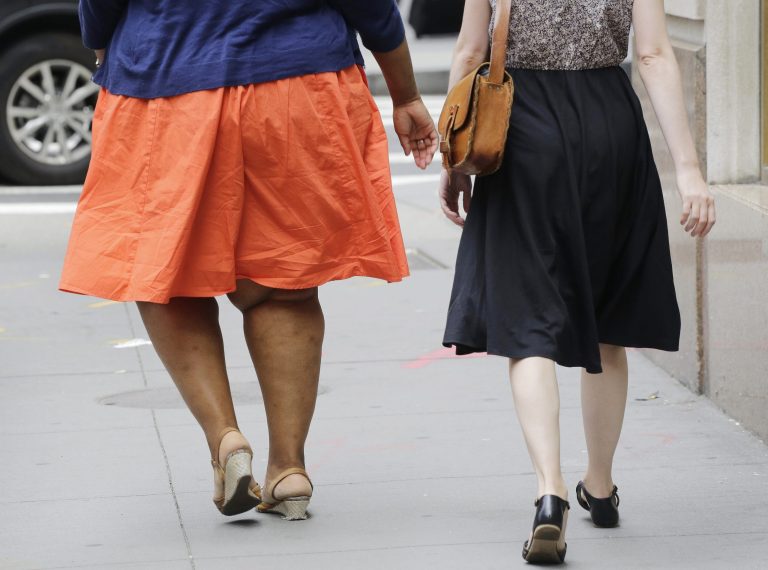 In this Monday, July 13, 2015 photo, an obese woman, left, walks in New York. One-third of American adults and one in six children are now obese, although an annual report released Thursday by two nonprofit groups found that rates could be stabilizing. The report noted that 25 states had obesity rates above 30 percent. In 2000, no state had a rate above 25 percent. (AP Photo/Mark Lennihan)