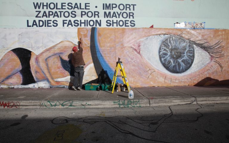   Artist Scott Debus spray-paints a mural on the wall of a warehouse in the Wynwood district of Miami, Monday, Dec. 3, 2012. Art Basel Miami Beach and about two dozen other independent art fairs open Thursday. Tens of thousands of people are expected through Sunday at the fairs throughout Miami and South Beach. (AP Photo/Wilfredo Lee)  