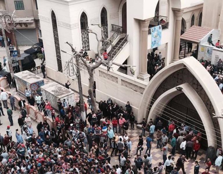 Relatives and onlookers swarm around a car outside a church after a bomb attack in the Nile Delta town of Tanta, Egypt, Sunday, April 9, 2017. The attack took place on Palm Sunday, the start of the Holy Week leading up to Easter, when the church in the Nile Delta town of Tanta was packed with worshippers. (AP Photo/Nariman El-Mofty)