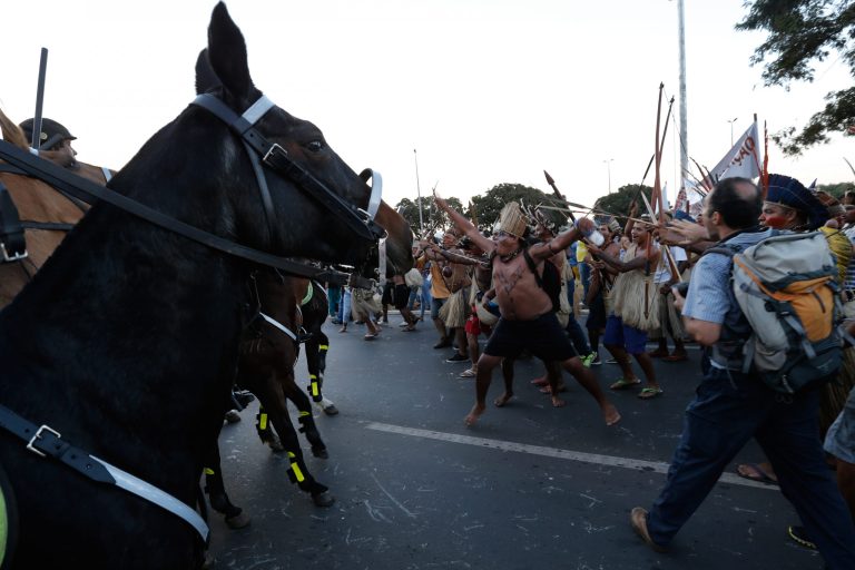 Indians clash with military police during a protest against the FIFA World Cup outside the National Stadium in Brasilia, Brazil, Tuesday, May 27, 2014. Brazil's indigenous communities calling for the federal court to demarcate indigenous lands are also protesting against the 2014 FIFA World Cup that starts in June. (AP Photo/Eraldo Peres)