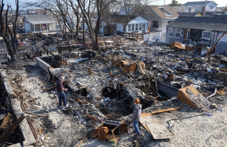 John Hardy, left, and his son, Liam, 13, visit the charred remains of his wife's parents home in the Breezy Point section of the Queens borough of New York, Friday, Nov. 23, 2012. (AP Photo/Mark Lennihan)