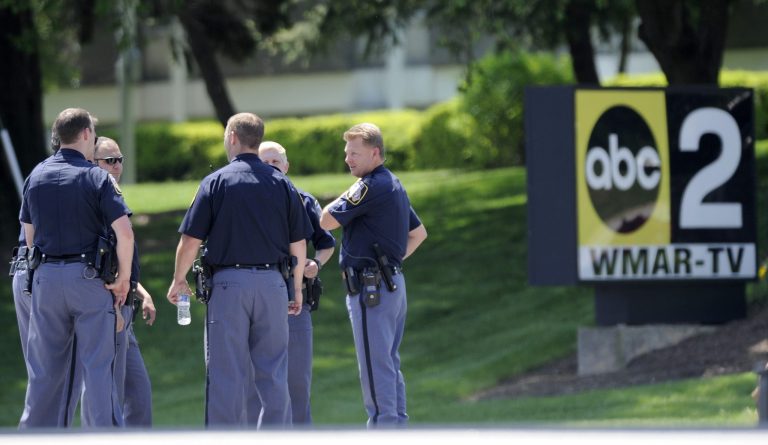 Police officers stand outside WMAR-TV, after a truck driven by a man rammed the Baltimore-area television station Tuesday, May 13, 2014 leaving a gaping hole in the front of the building, in Towson, Md. Police were still searching for the driver. They said they didn't know of a motive and didn't find weapons in the truck, but they assumed the driver may be dangerous because he ran into the occupied building.  The station believes everyone inside evacuated safely, News Director Kelly Groft said. (AP Photo/Steve Ruark)