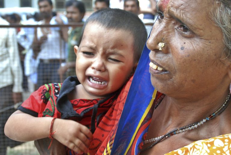 A woman holds a crying child as relatives of victims gather at the spot of a stampede at the Kamta Nath Hindu temple in Chitrakoot, India, Monday, Aug. 25, 2014. A pre-dawn stampede killed 10 people Monday as tens of thousands of Hindus were worshipping in an annual procession marking the holy day of Somvati Amavasya. (AP Photo/Amar Deep)