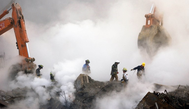 In this Oct. 11, 2001 file photo, firefighters make their way over the ruins of the World Trade Center through clouds of smoke at ground zero in New York. Sixteen years of study has answered only a handful of questions about the hundreds of health conditions believed to be related to the tons of gray dust that fell on the city when the trade center collapsed, from post-traumatic stress disorder, asthma and respiratory illness to vitamin deficiencies, strange rashes and cancer. (AP Photo/Stan Honda, Pool)