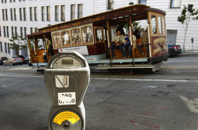 FILE - In this Oct. 27, 2009 file photo, a cable car passes a parking meter near San Francisco's financial district. San Francisco City Attorney Dennis Herrera on Monday, June 23, 2014 issued a cease-and-desist demand to a mobile app called Monkey Parking, which allows people to auction off public parking spaces that they're using to other nearby drivers. (AP Photo/Ben Margot, File)